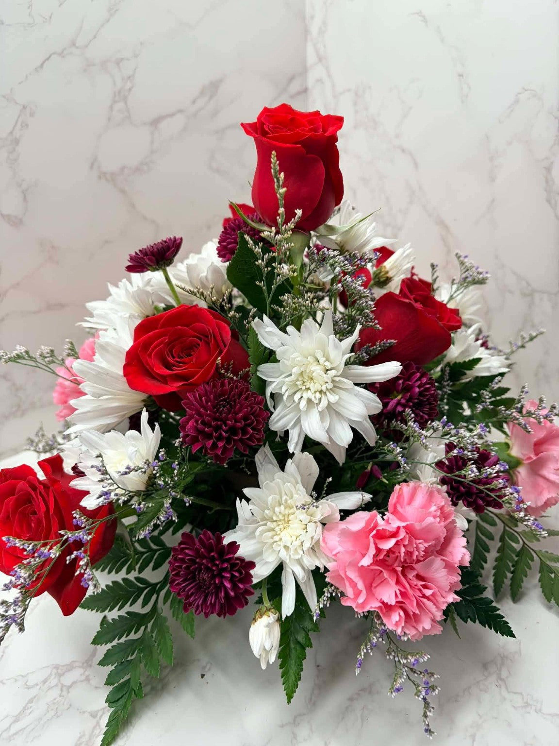 Rose Runners lush mixed flower arrangement with red roses, burgundy mums, pink carnations and white flowers