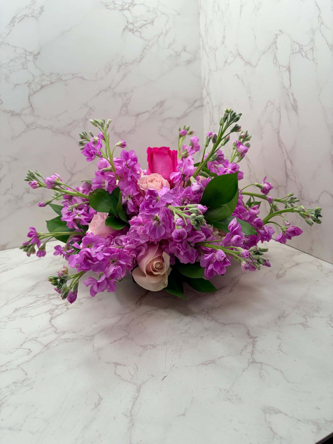 Rose Runners romantic pink roses and purple stock in a low floral arrangement