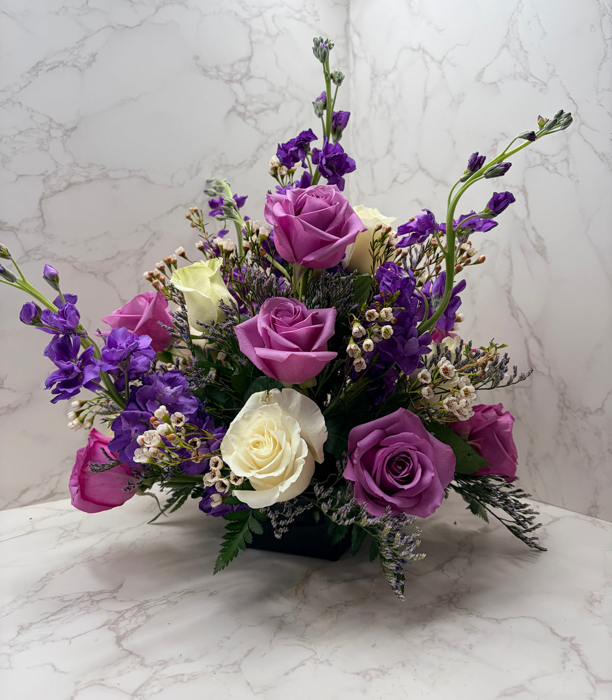 Rose Runners lavender purple roses and ivory roses with purple stock in a black container